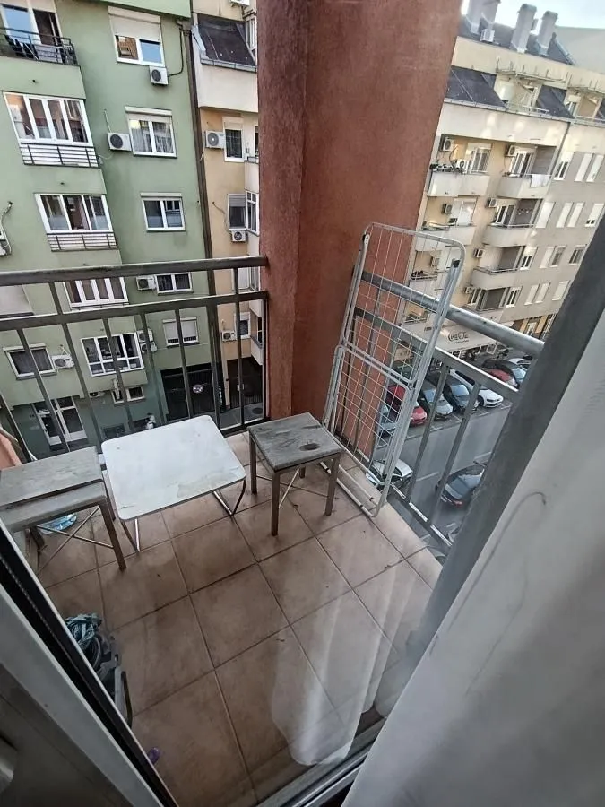 Small tiled balcony with a table, chairs, and a drying rack.