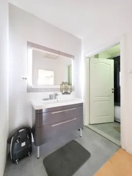 Bathroom with a vanity sink and a large illuminated mirror. - image 14