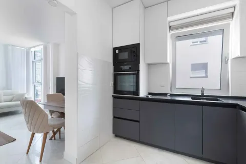 Modern kitchen with dark cabinetry and a view of the dining area. - image 13