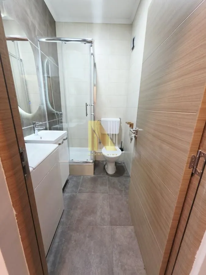Moderno kupatilo sa tuš kabinom, umivaonikom i WC šoljom.