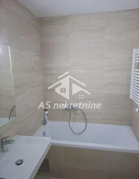 Bathroom equipped with a bathtub, washbasin, and neutral-toned tiles. - image 21