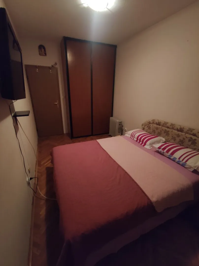 Jednostavno namještena spavaća soba sa bračnim krevetom i ormarom.