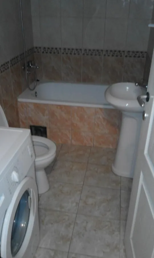 Kupatilo opremljeno kadom, umivaonikom, WC šoljom i veš mašinom.