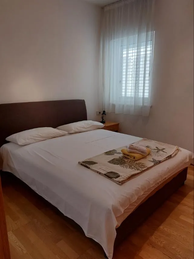 Jednostavno namještena spavaća soba sa bračnim krevetom i prozorom.