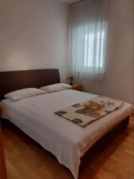Jednostavno namještena spavaća soba sa bračnim krevetom i prozorom. - image 5