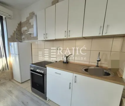 Small kitchen with white cabinets, stove, and refrigerator. - image 3