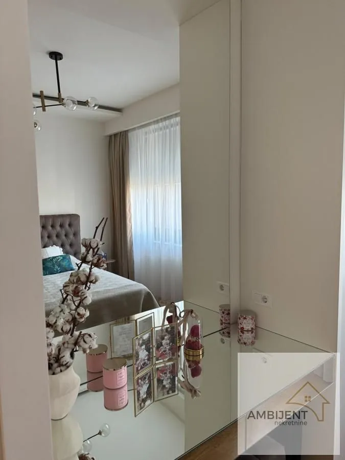 Pogled iz hodnika ka spavaćoj sobi sa krevetom i ogledalom.