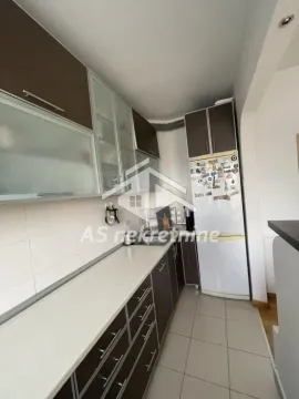 Kuhinja sa tamnim elementima i belim frižiderom. - image 8