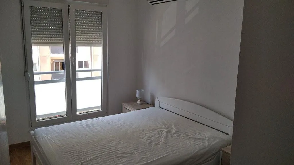 Bedroom with a double bed, nightstand, and balcony doors.