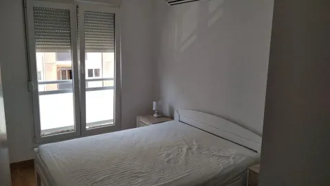 Bedroom with a double bed, nightstand, and balcony doors. - image 11