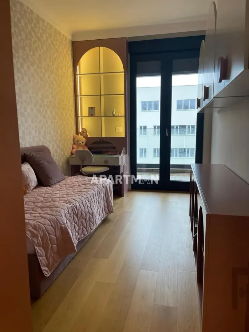 Dečja soba sa krevetom, radnim stolom i izlazom na terasu.