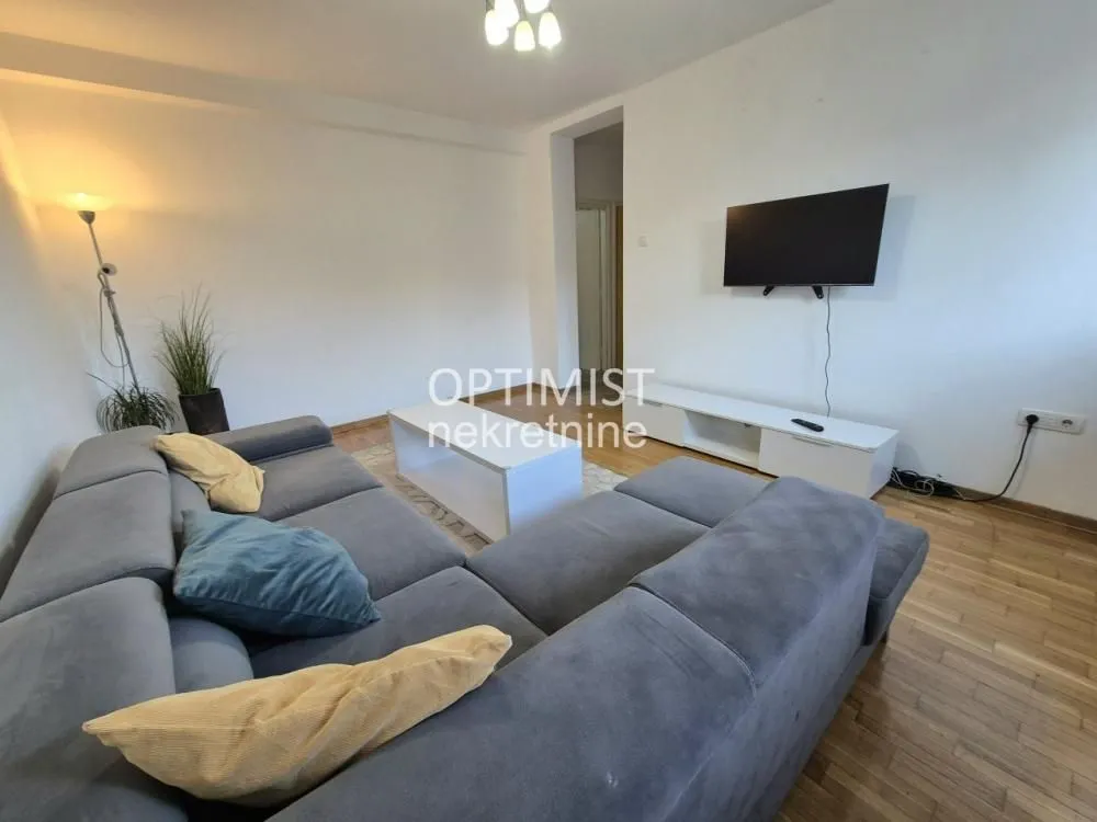 Living room with a sectional sofa, coffee table, and wall-mounted TV.