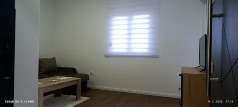 Living room with a sofa, coffee table, TV, and window with blinds. - image 4
