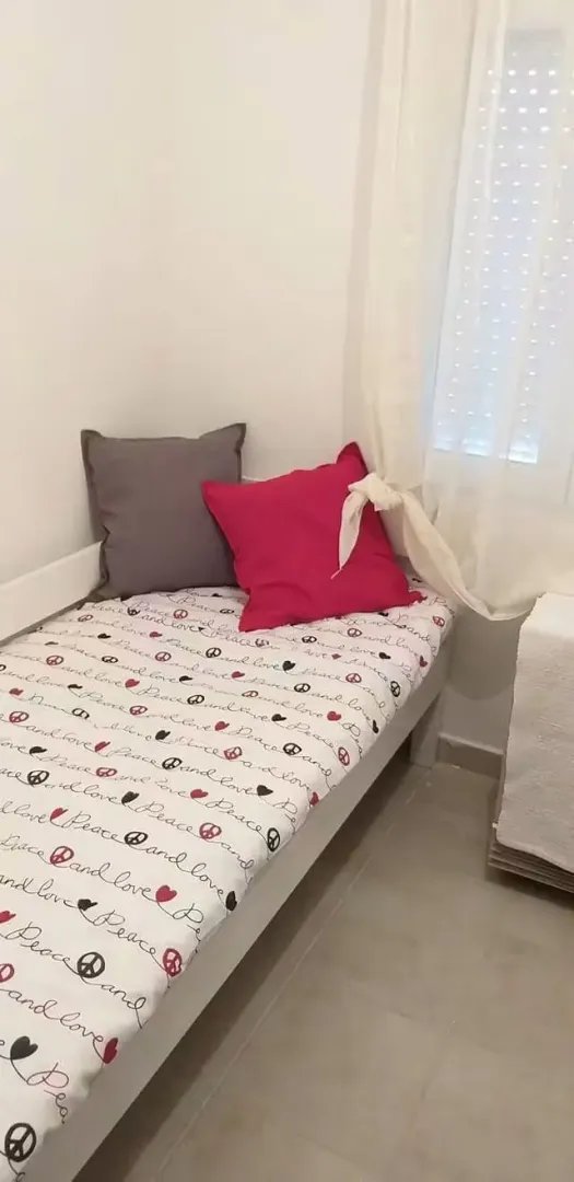 Small bedroom with a bed and pillows near the window.