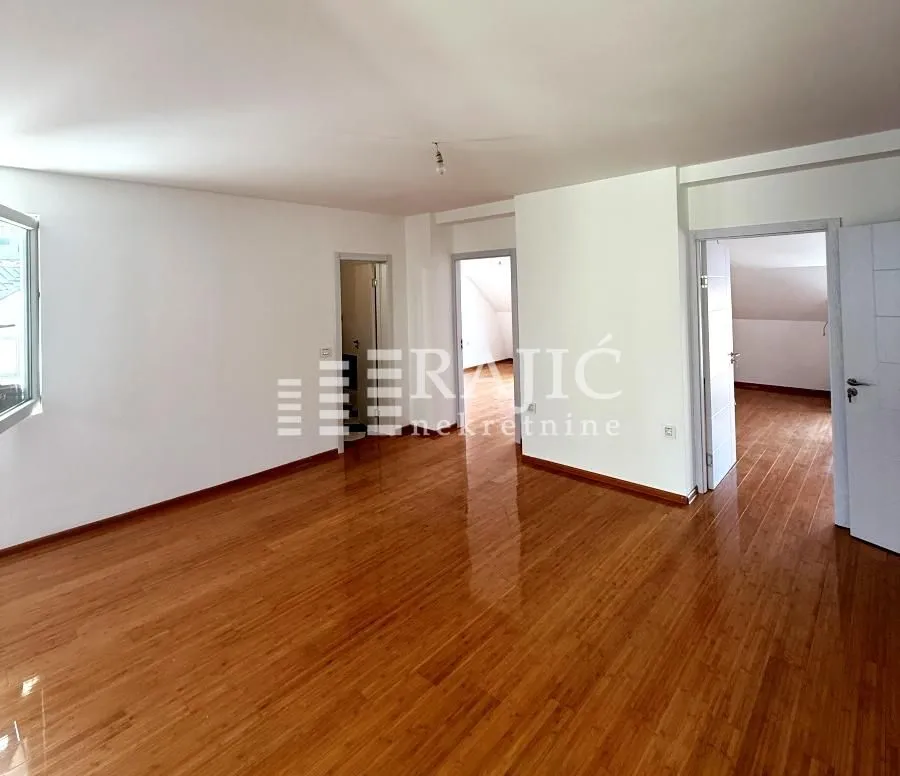 Empty room with wooden flooring and white walls.
