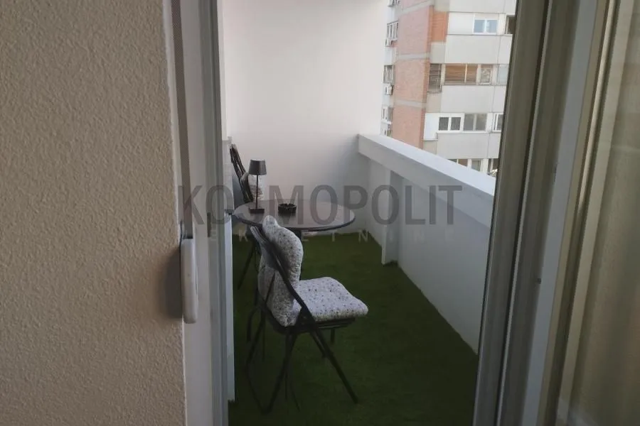 Manji namešten balkon sa stolom i stolicama.