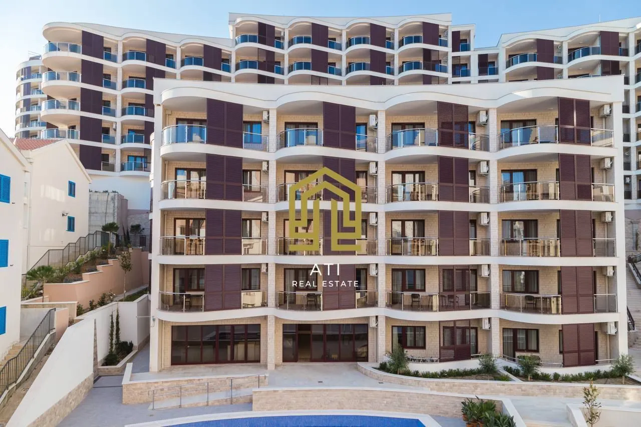 Exterior view of a modern residential building with balconies and a swimming pool.