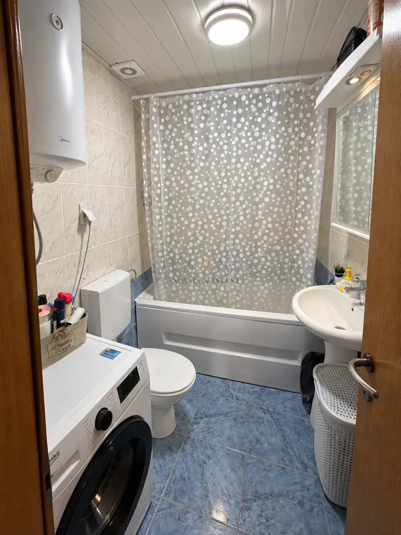 Small bathroom with a bathtub, washbasin, toilet, and washing machine.