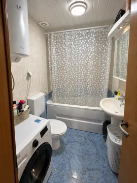 Small bathroom with a bathtub, washbasin, toilet, and washing machine. - image 11
