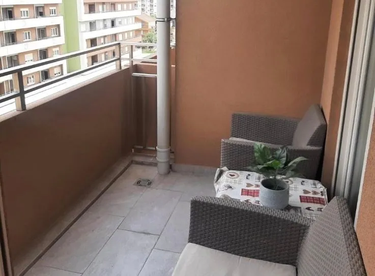 Furnished balcony with seating set and view of surrounding buildings.