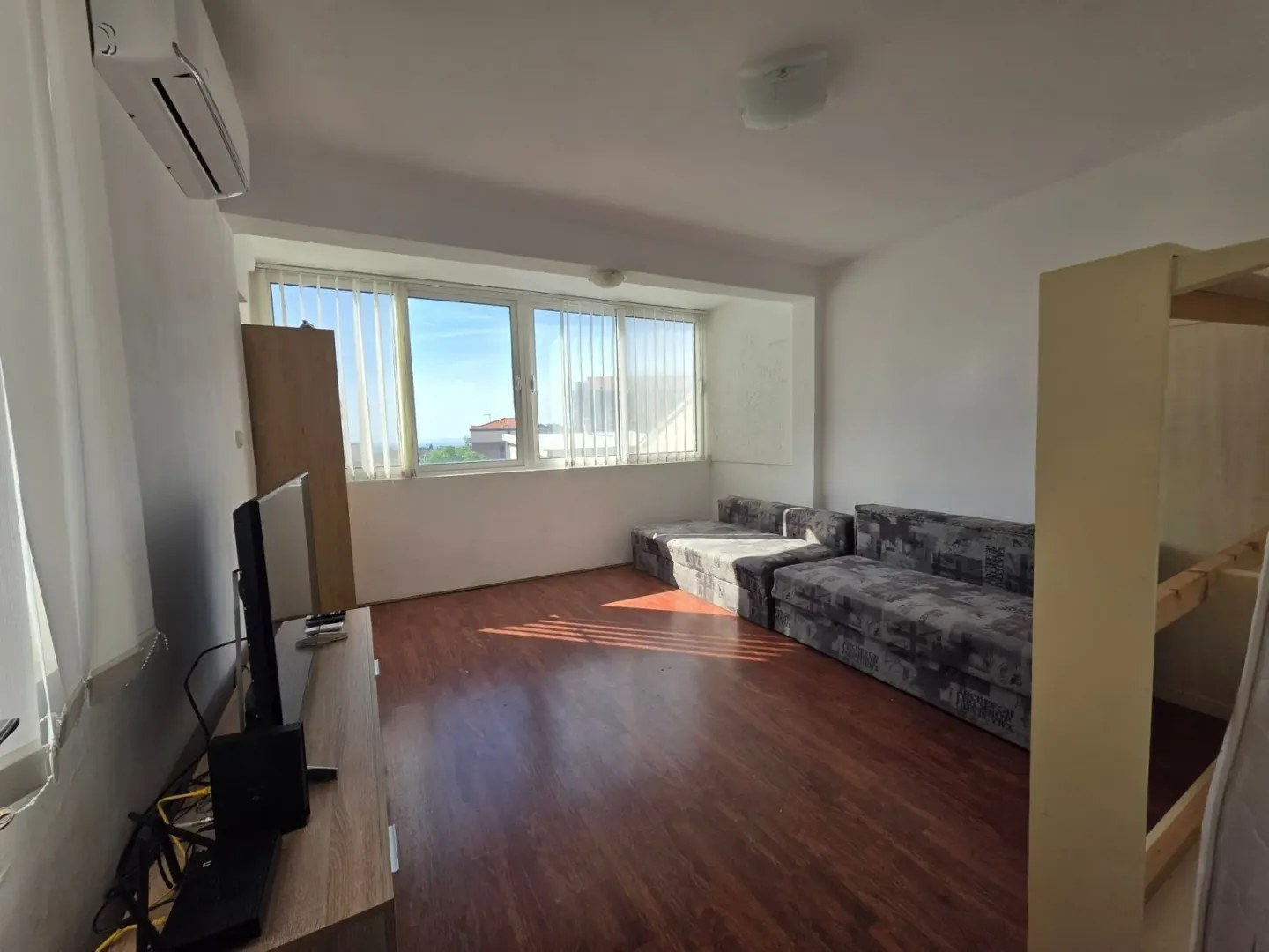 Living room with a sofa, TV unit, and large window.