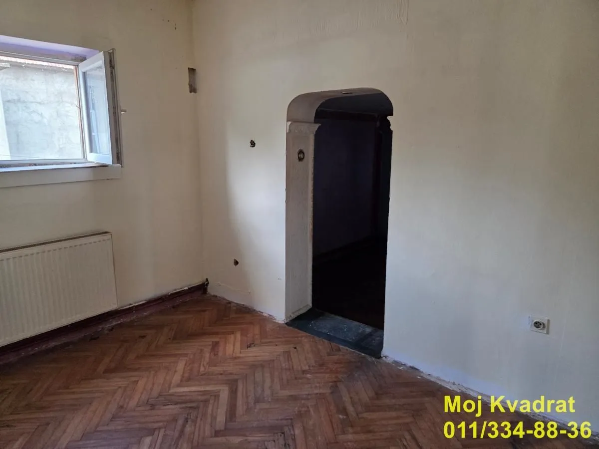 Prazna prostorija sa parketom i prozorom.