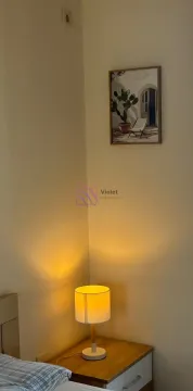 Noćni stočić sa lampom i uramljenom slikom na zidu u spavaćoj sobi. - image 4