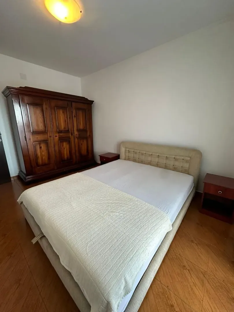 Namještena spavaća soba sa bračnim krevetom, velikim drvenim ormarom i dva noćna stočića.