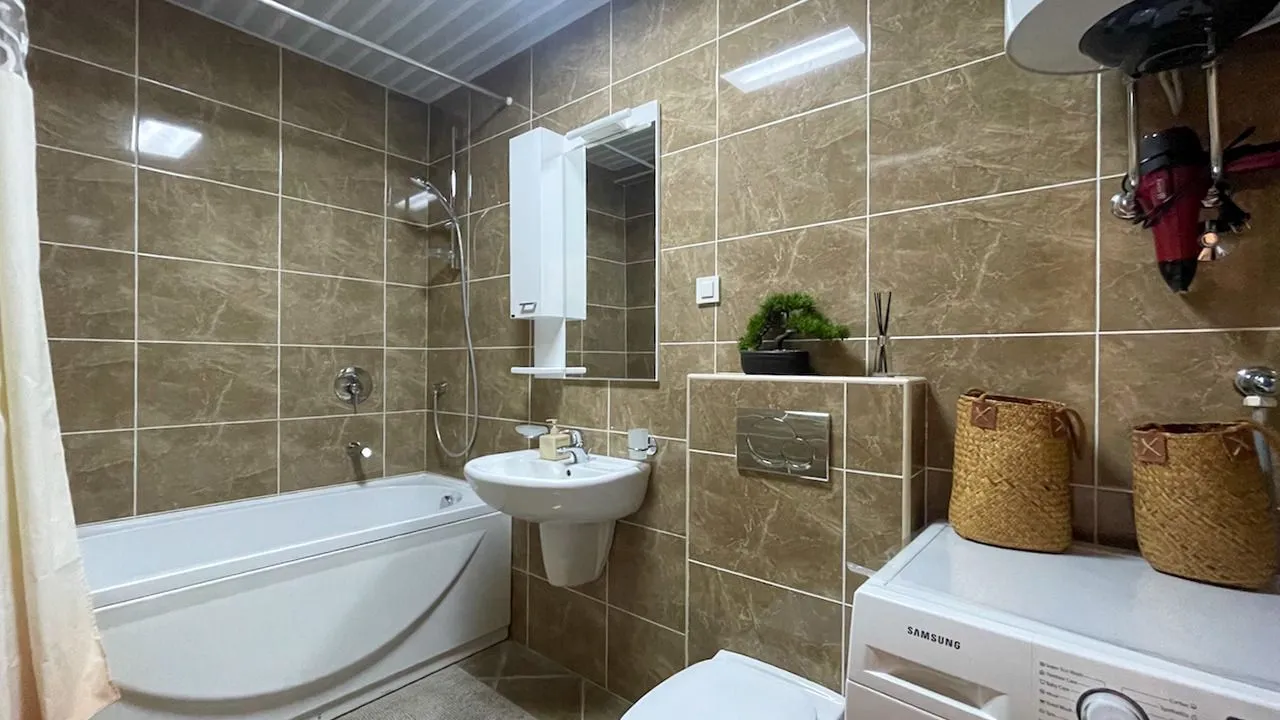 Kupatilo opremljeno kadom, umivaonikom, WC šoljom i veš mašinom.