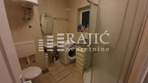 Smaller bathroom with a shower cabin, sink, toilet, and washing machine. - image 10