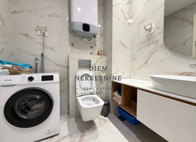 Modernly equipped bathroom with a washing machine and marble tiles.