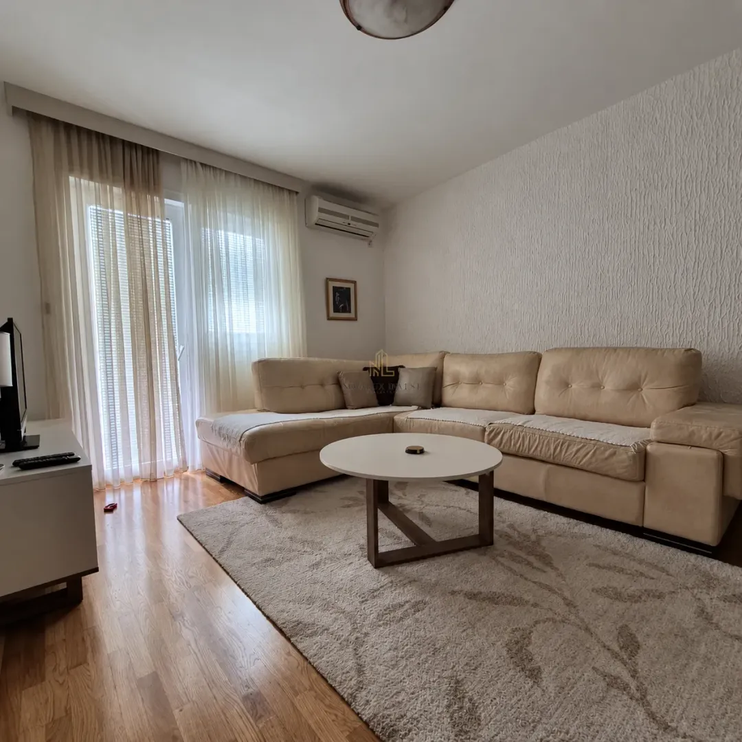 Dnevna soba sa ugaonom garniturom, stočićem i izlazom na terasu.