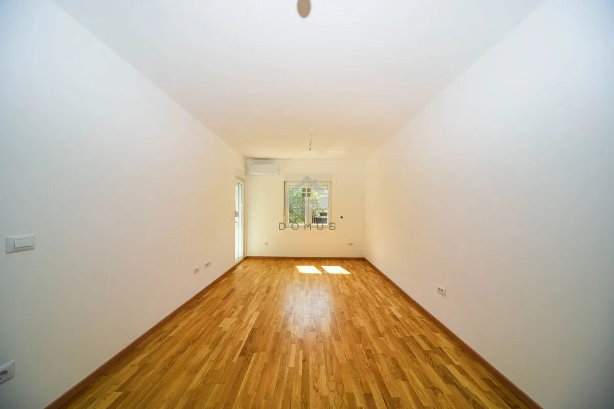 Empty room with white walls and wooden parquet flooring.