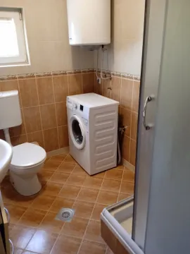 Smaller bathroom with a shower cabin, toilet, and washing machine. - image 11