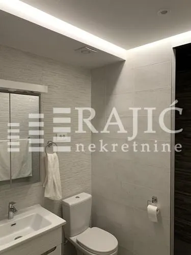 Modern bathroom with a sink, toilet, and mirror.