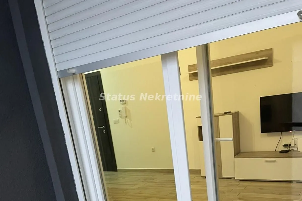 Pogled kroz balkonska vrata na nameštenu dnevnu sobu.