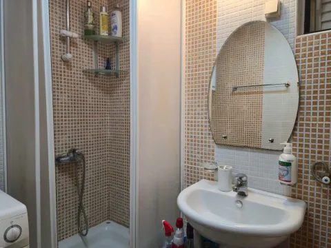 Smaller bathroom with a shower cabin, washbasin, and mirror. - image 9