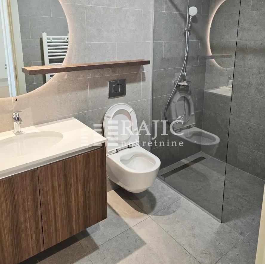 Modern bathroom with a sink, walk-in shower, and toilet.