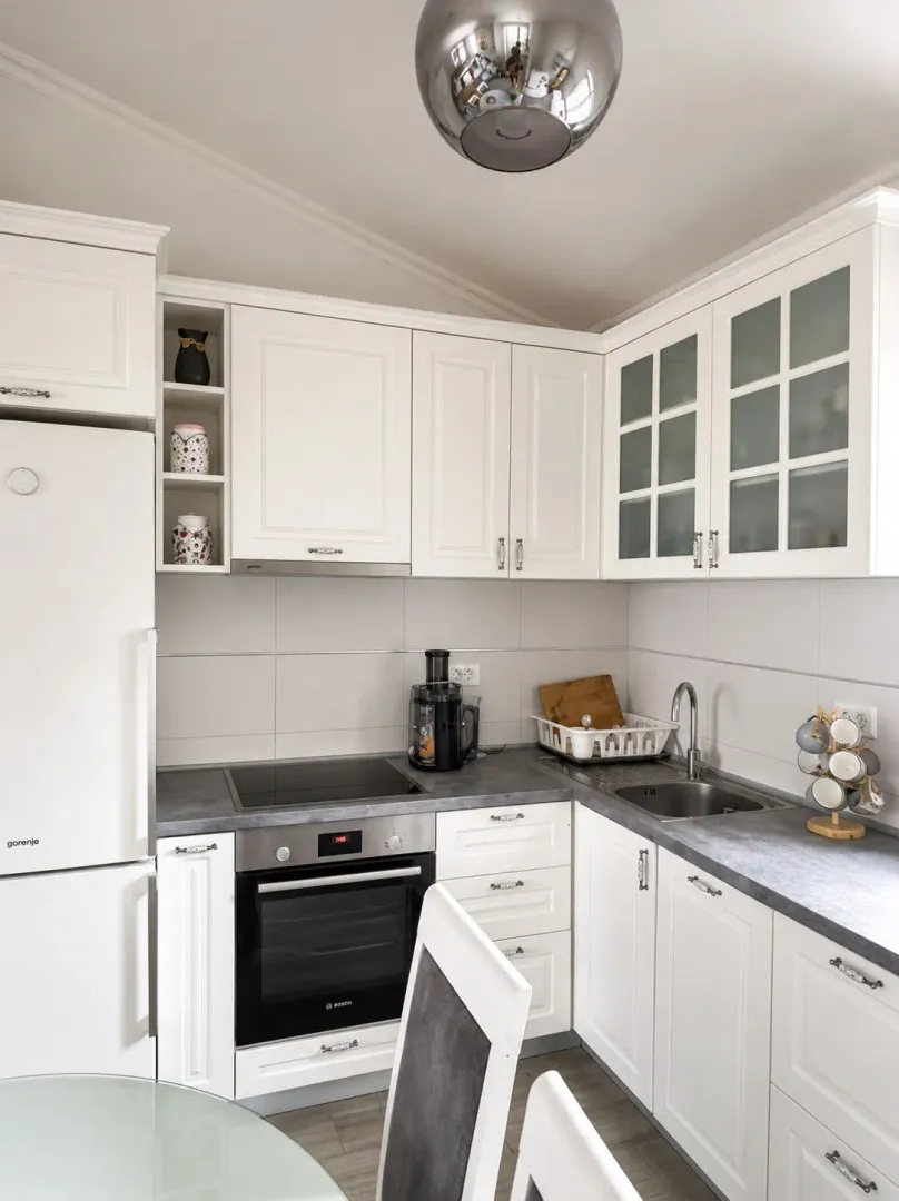 Modern white kitchen with built-in appliances and dark countertops.