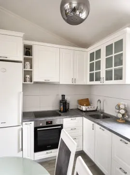 Modern white kitchen with built-in appliances and dark countertops. - image 11