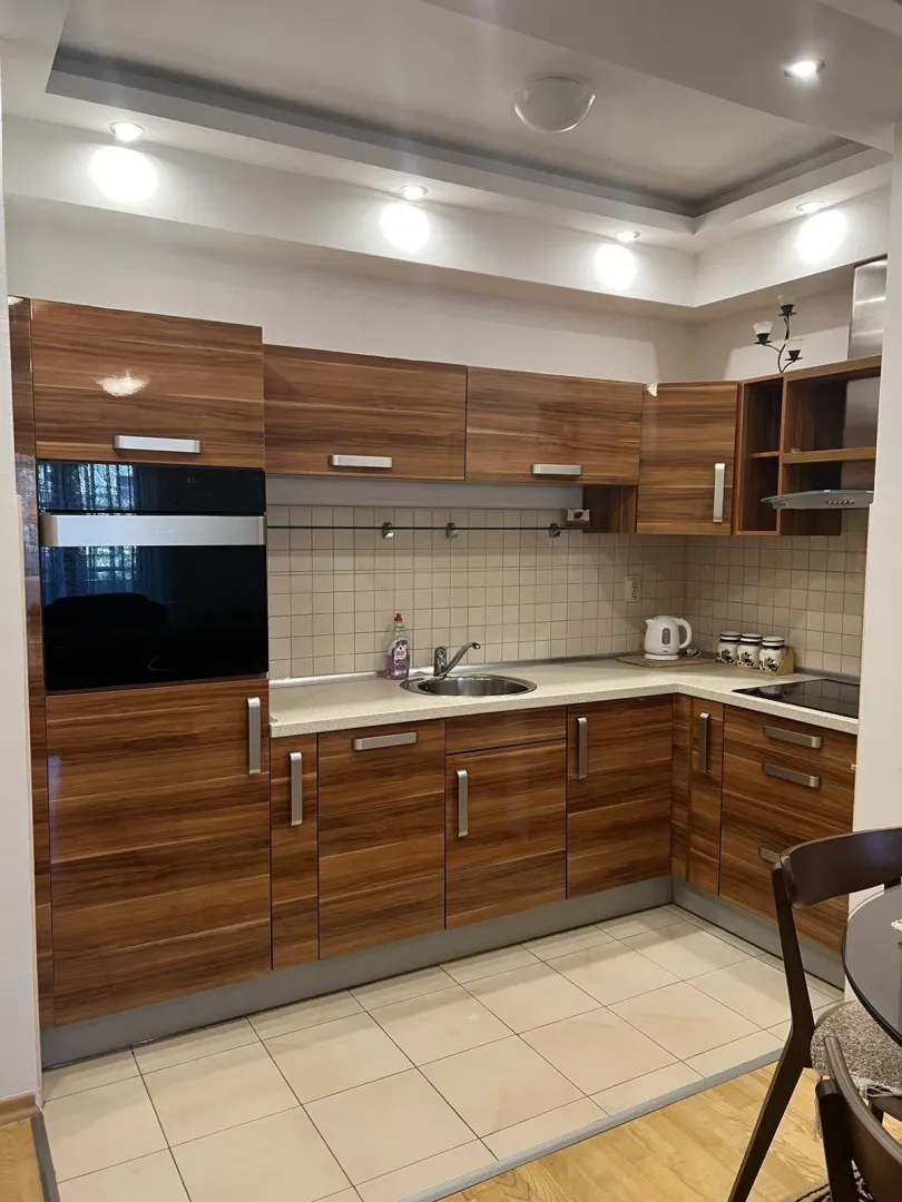 Kitchen with wooden cabinets, a built-in oven, and light-colored tiles.