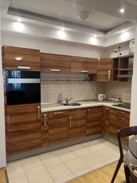 Kitchen with wooden cabinets, a built-in oven, and light-colored tiles. - image 10