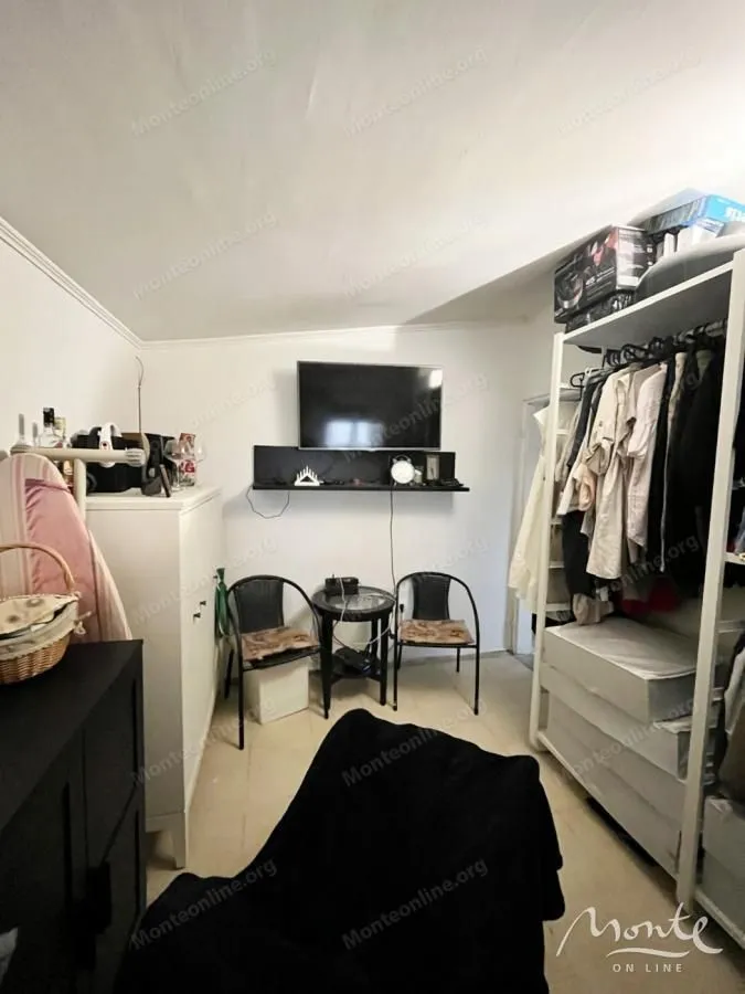 Manja spavaća soba sa ormarima, TV-om i stolom sa dvije stolice.