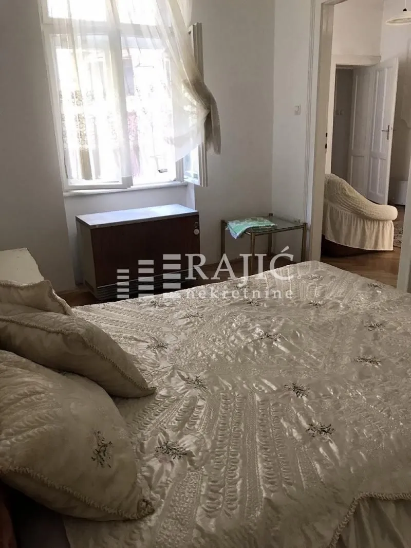 Furnished bedroom with a large double bed and a window.
