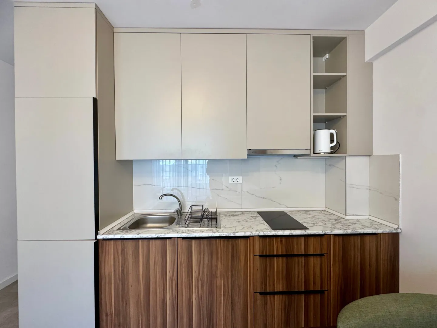 Modern kitchen with light upper and wooden lower cabinets.