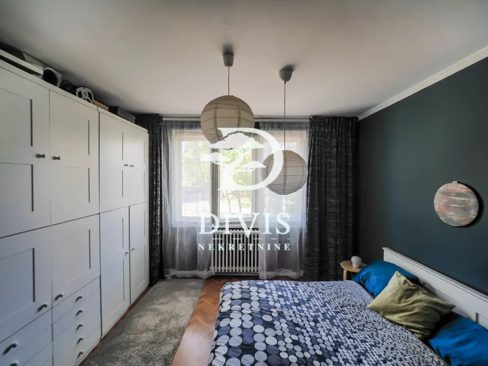 Bedroom with a double bed, a large white wardrobe, and a window.