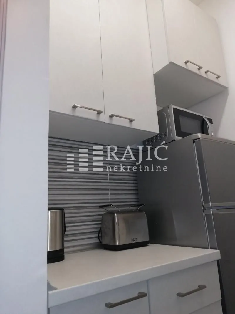 Part of a modern kitchen with white cabinets, a refrigerator, and home appliances.
