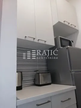 Part of a modern kitchen with white cabinets, a refrigerator, and home appliances. - image 5