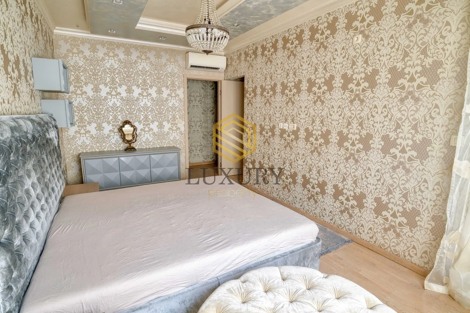Bedroom with a double bed, patterned wallpaper, and a chandelier.