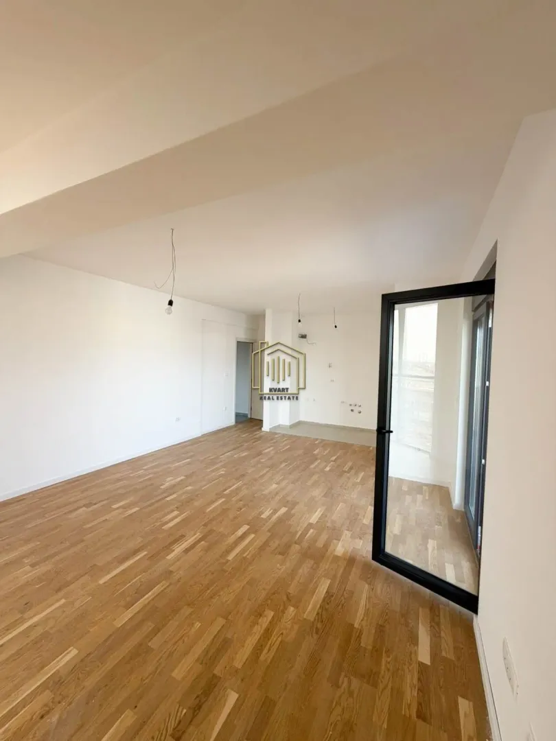 Empty living room with hardwood flooring and access to the terrace.